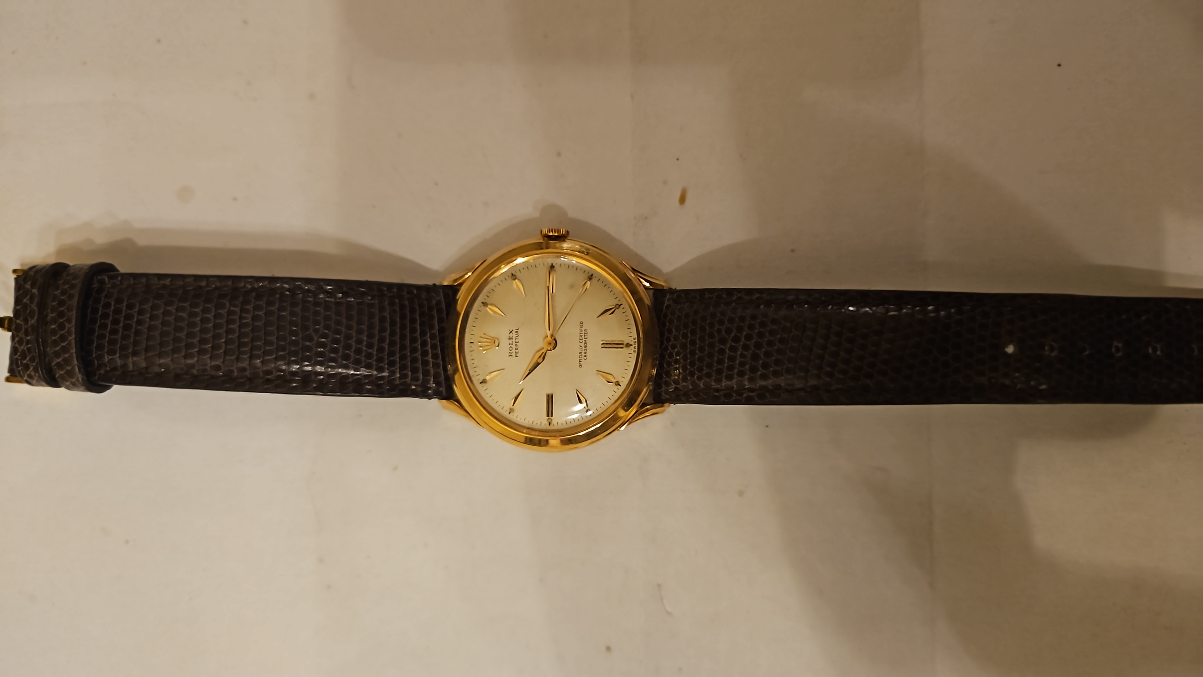 Montre ronde dorée à cadran clair et bracelet noir texturé
