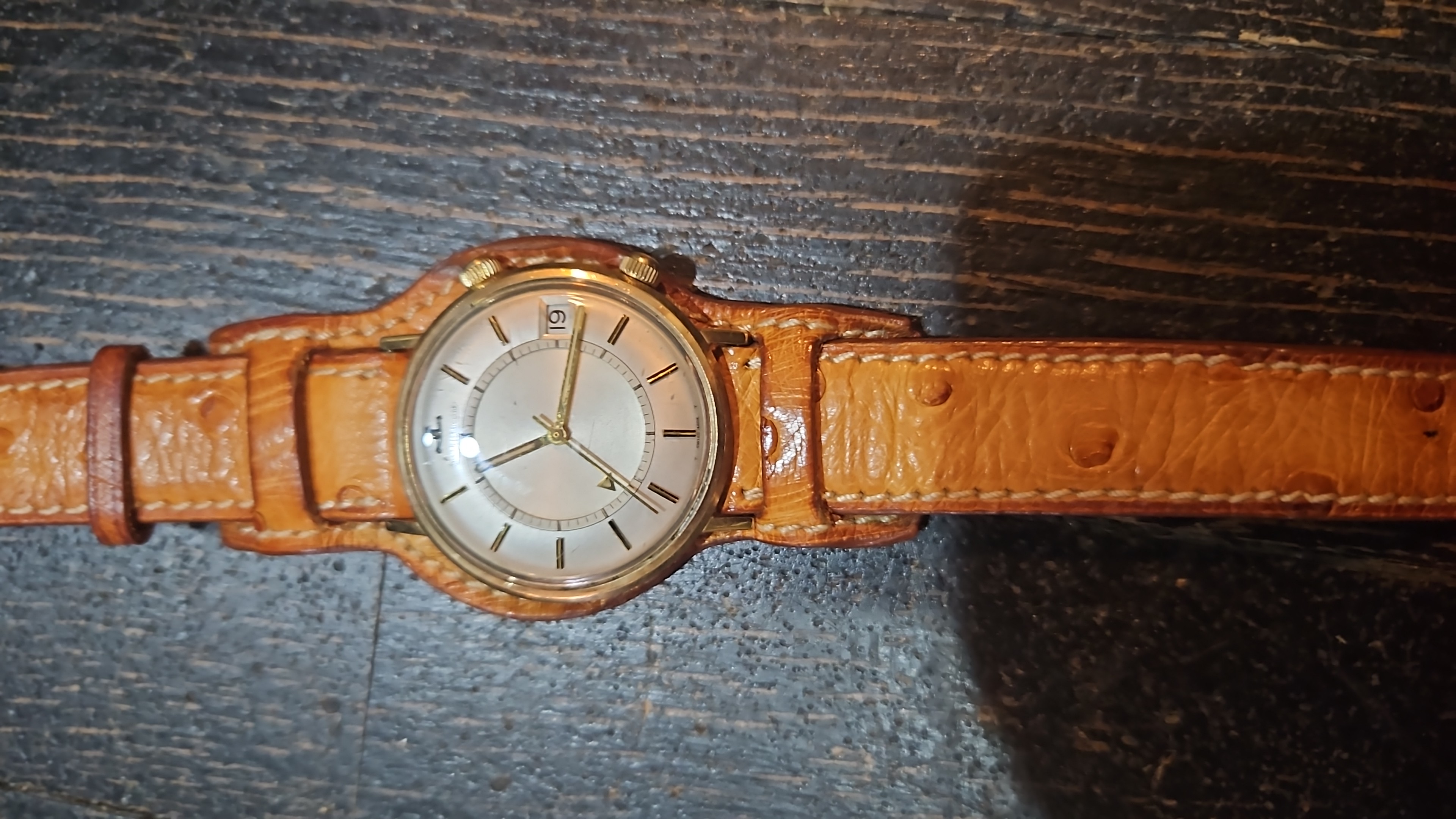 Montre ronde dorée à cadran clair et bracelet brun en cuir