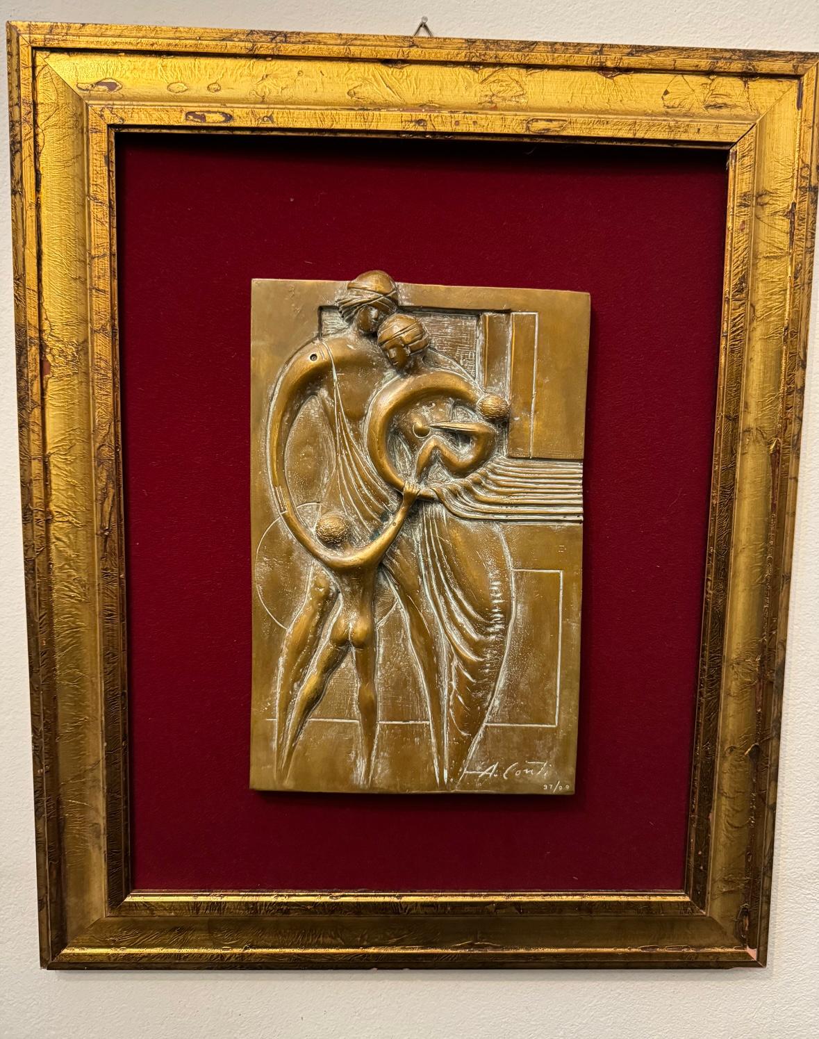 Petit relief doré représentant une figure agenouillée, encadré sur fond rouge