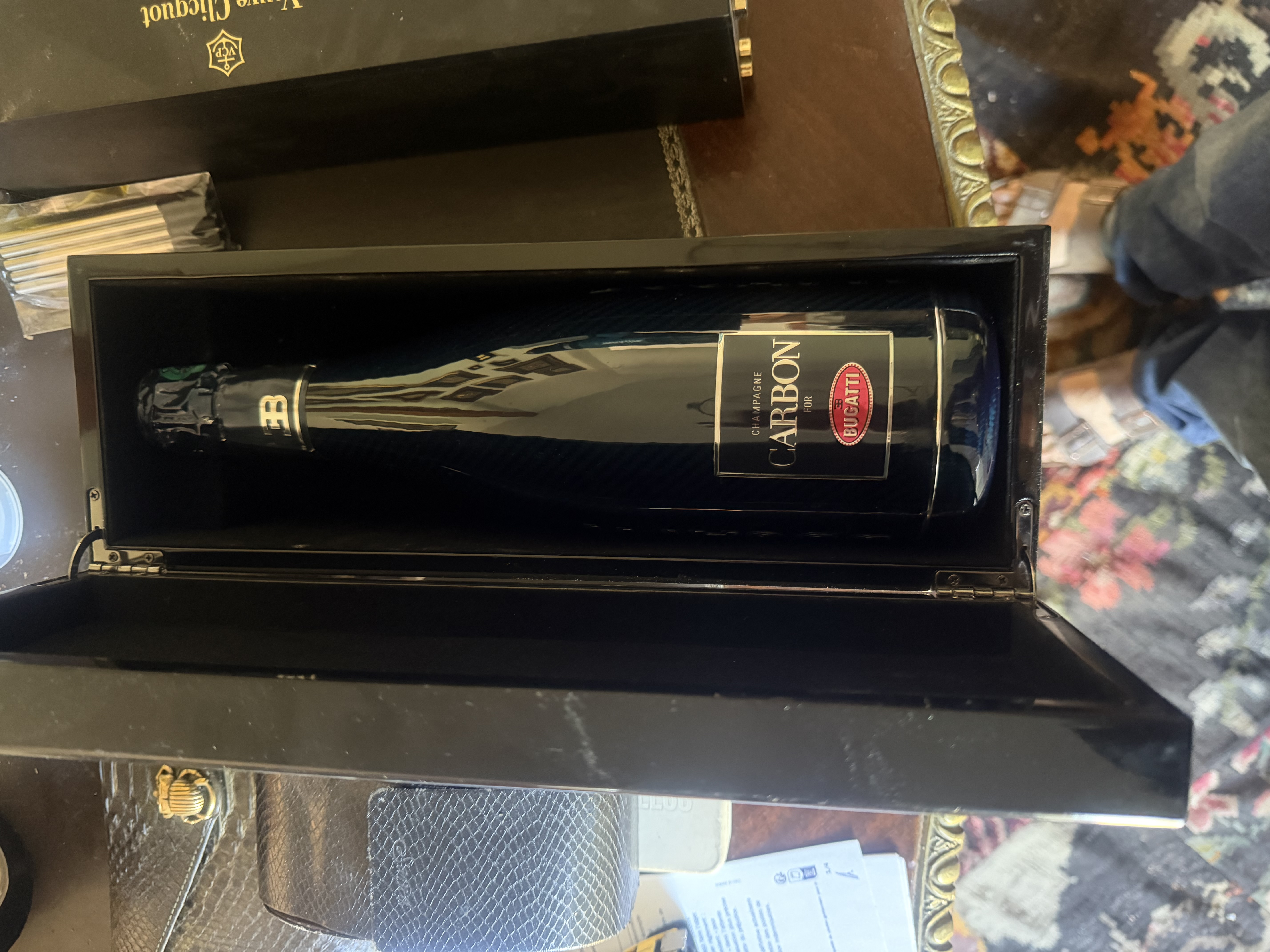 Bouteille sombre décorée de lignes dorées, présentée dans un coffret noir