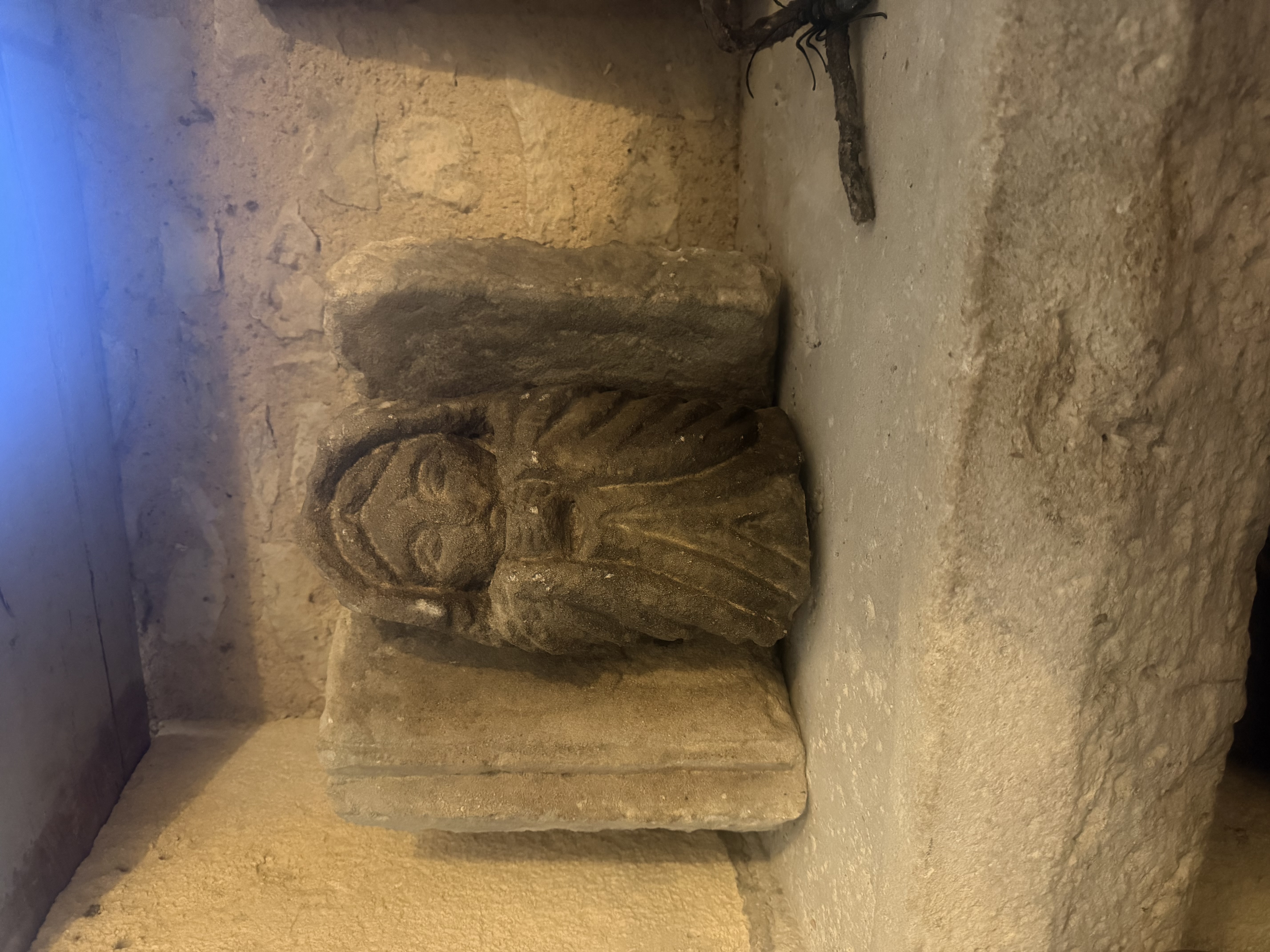 Visage sculpté dans un bloc de pierre intégré à un mur ancien