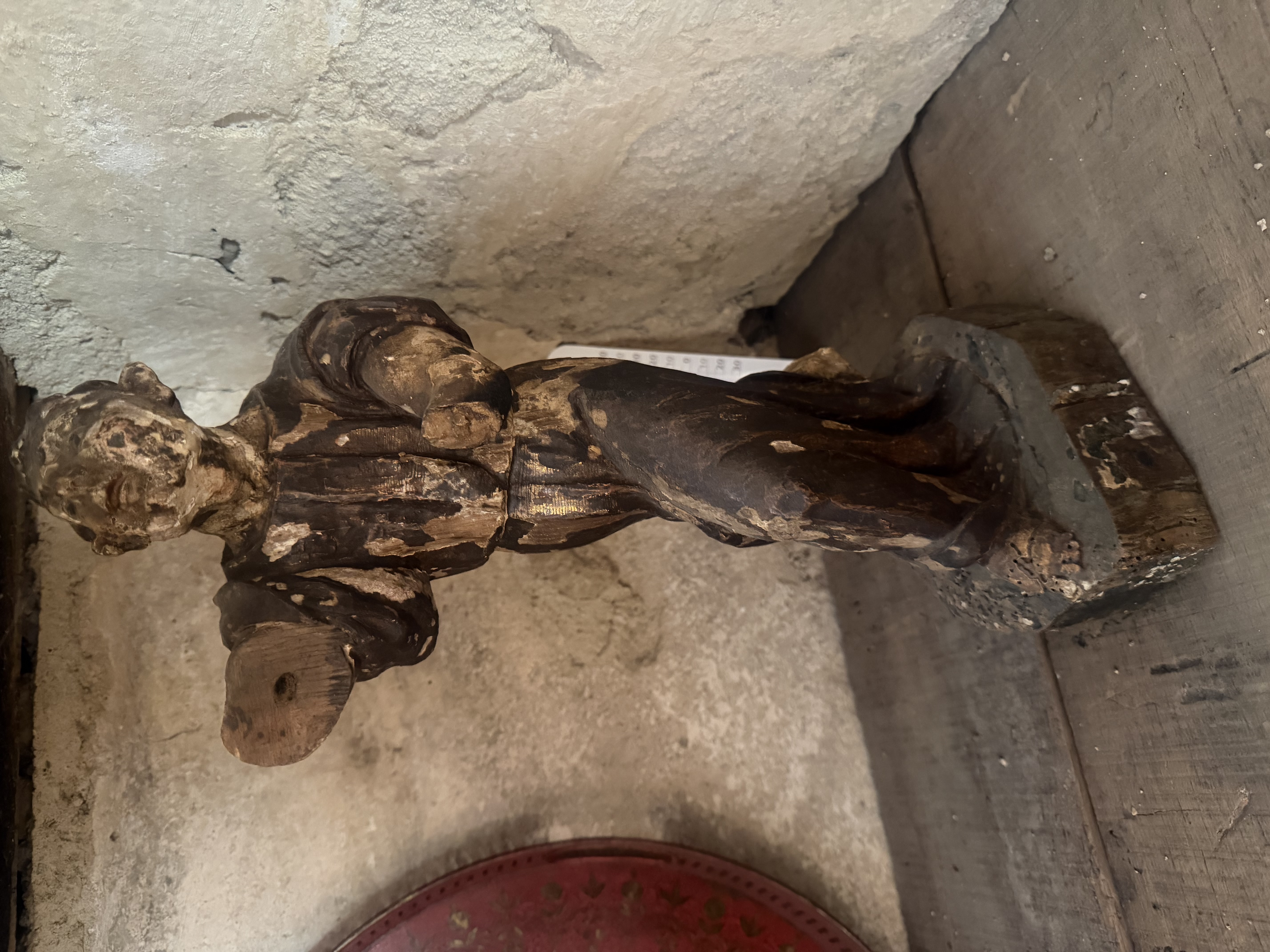 Petite figure ancienne en bois sombre, usée et partiellement érodée