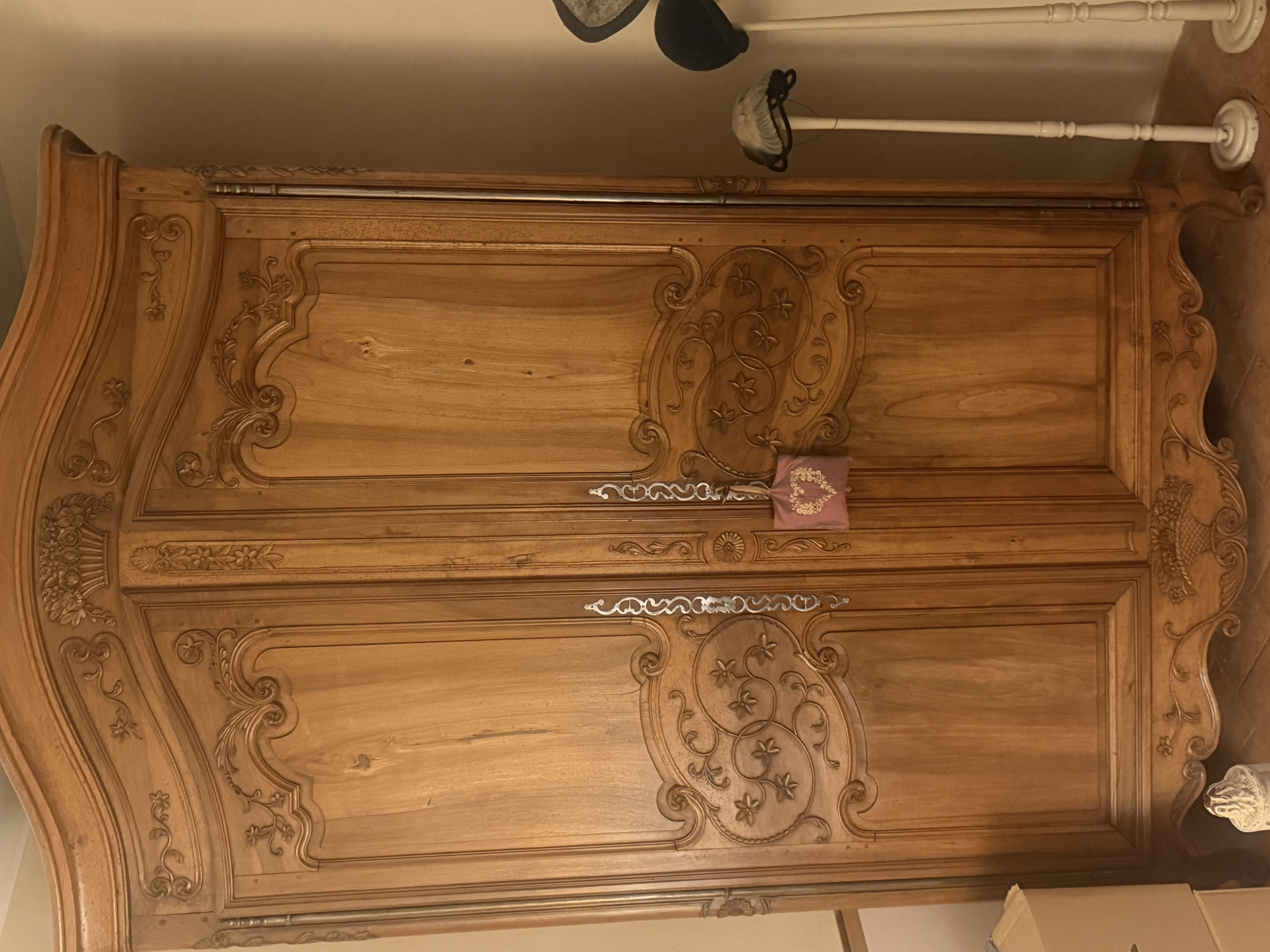 Grande armoire en bois clair aux panneaux et traverses richement sculptés